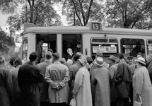 858954 Afbeelding van een gezelschap bij de tramhalte voor het N.S.-station Amsterdam C.S. te Amsterdam, ter ...